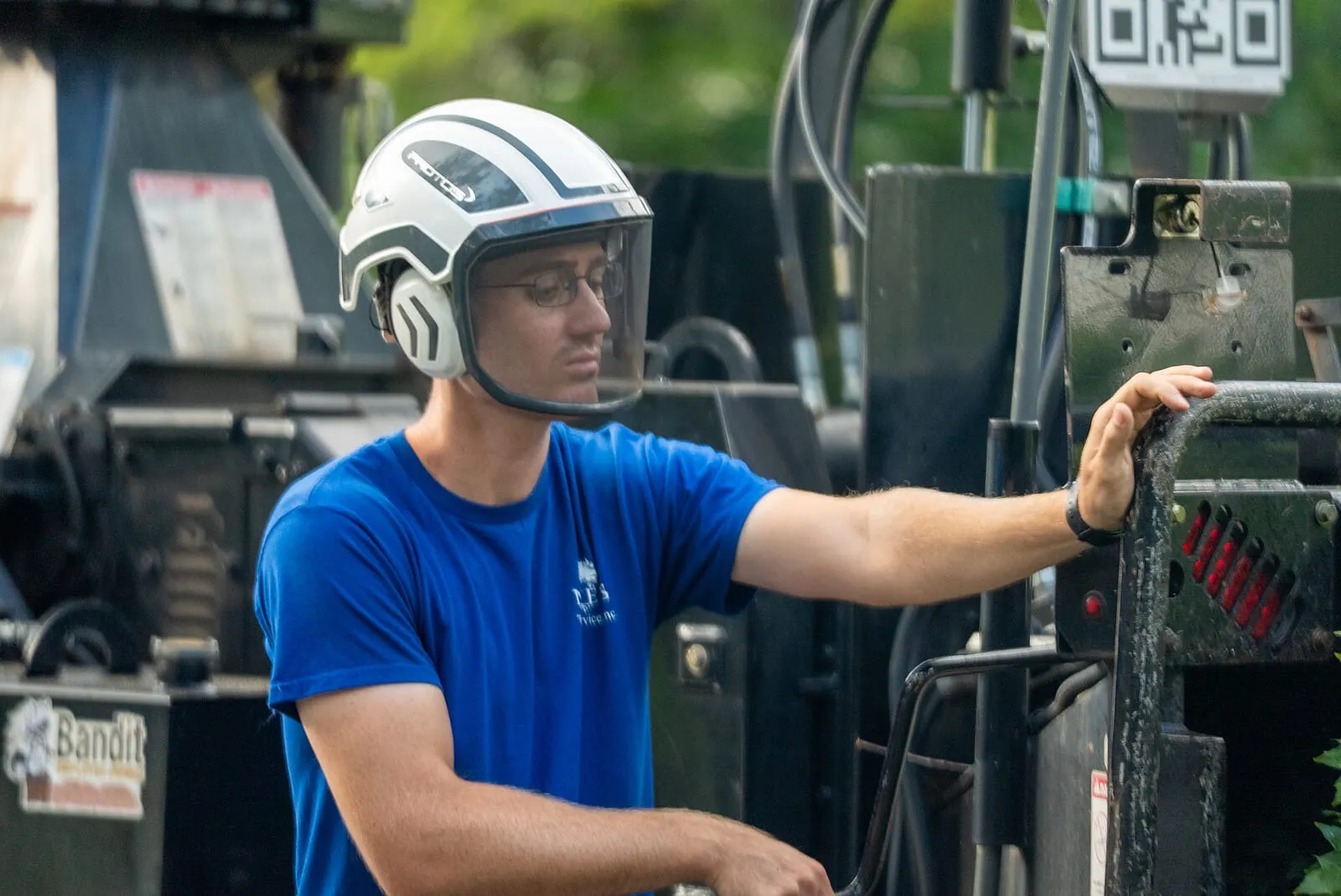 Crew member in helmet and face shield at the chipper controls
