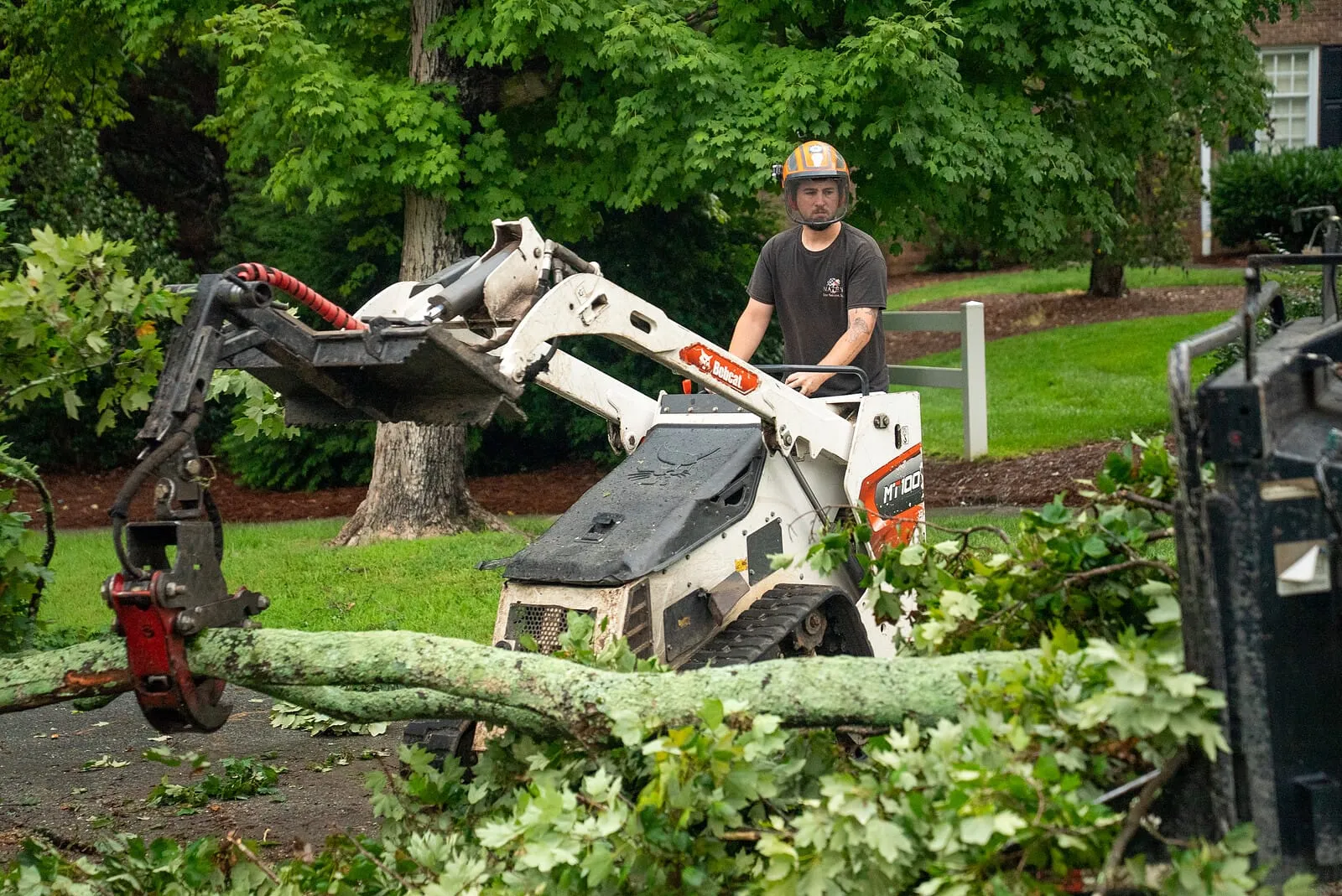 Compact track loader moving brush on a lot being cleared