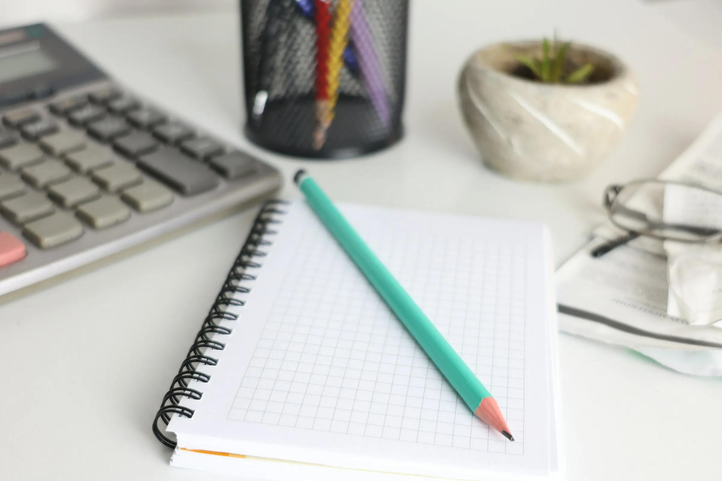 Notebook, pencil, calculator, and glasses on a bright planning desk